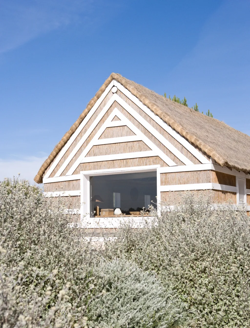 Thatched cottage with white geometric framing amid low shrubs, Jacques Grange, Comporta