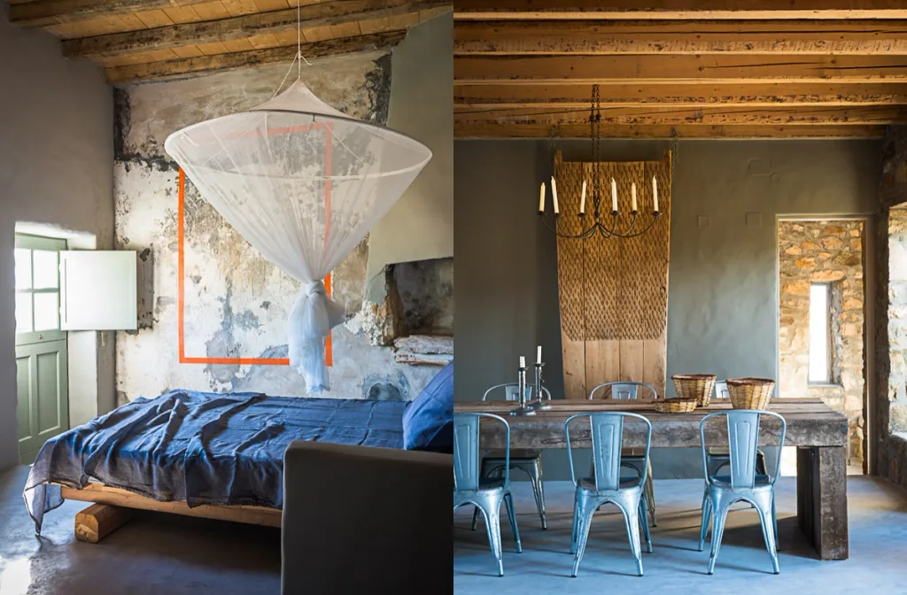Blue bed beneath a mosquito net paired with a wooden dining table and metal chairs in Serifos