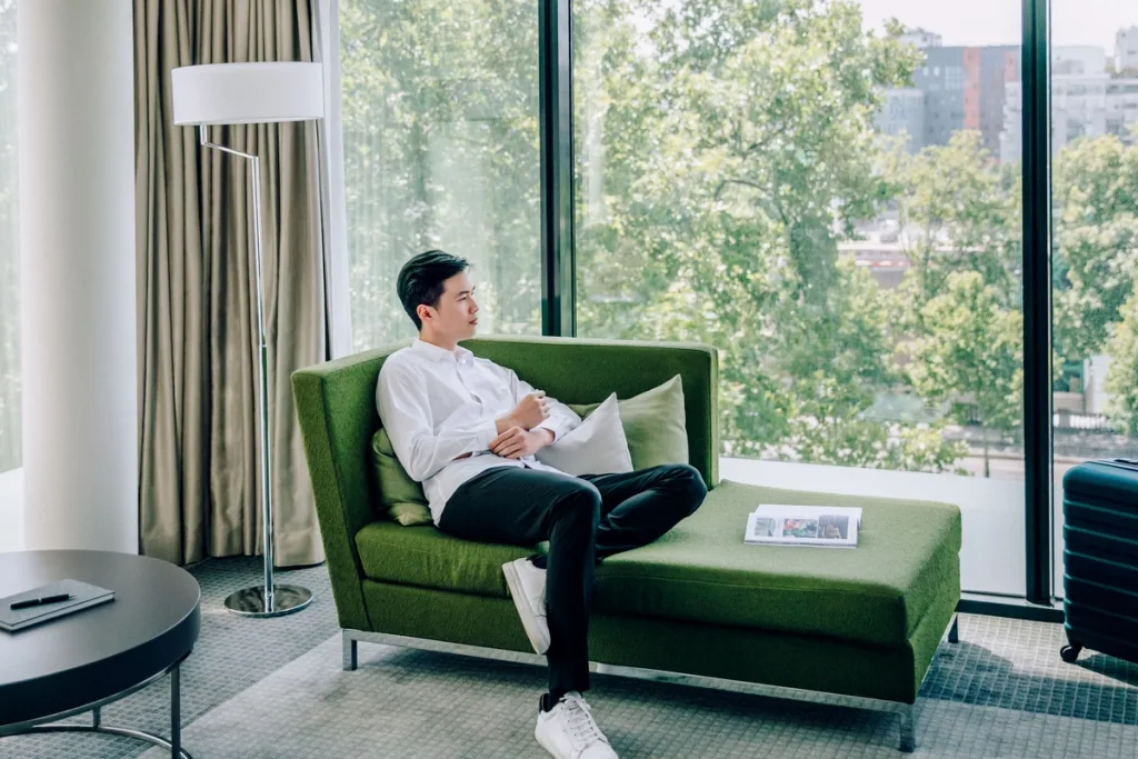 Guest relaxing on a green chaise lounge overlooking the treetops, Pullman Bercy hotel