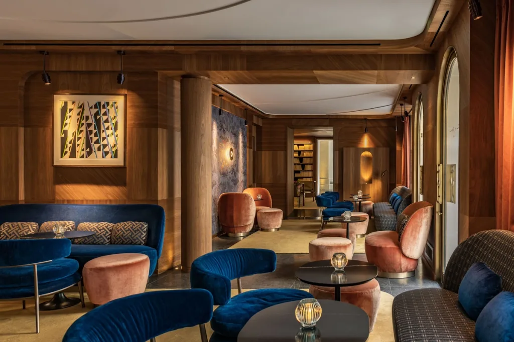 Wood-paneled lounge with blue velvet sofas and terracotta armchairs at Hotel Pavillon St Germain, Paris