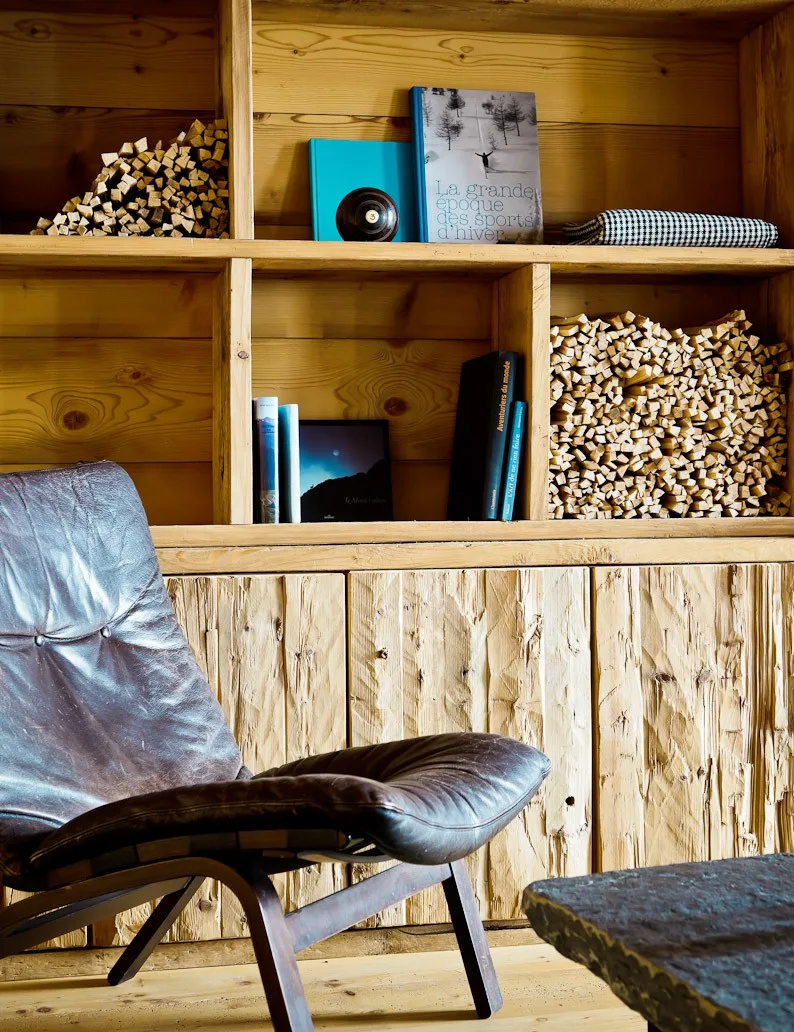 Bookshelf stacked with firewood and books beside a leather lounge chair at Montagne Alternative hotel, Switzerland