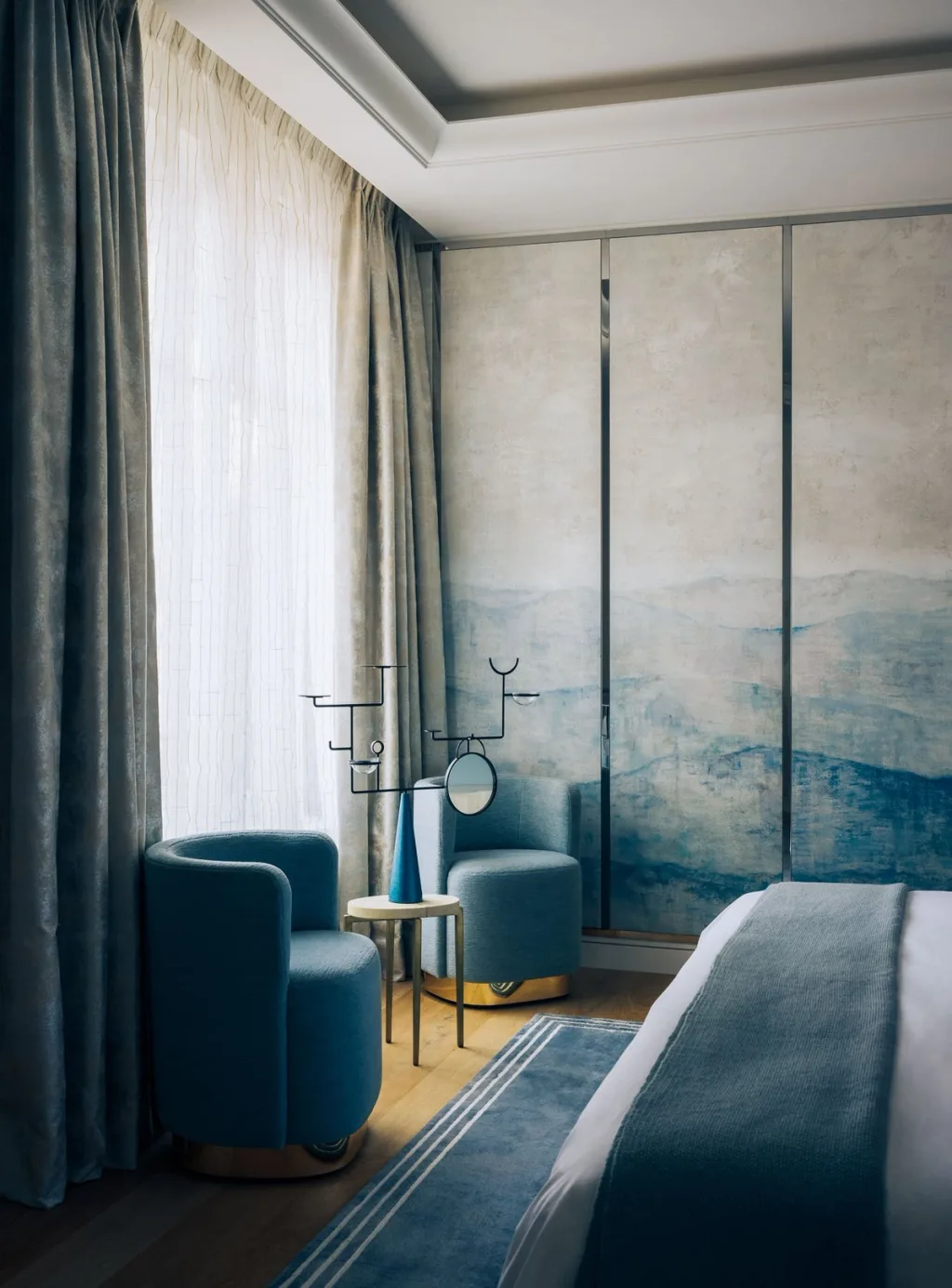 Two blue bedroom chairs beside painted wall panels in Stéphanie Coutas' Paris interior
