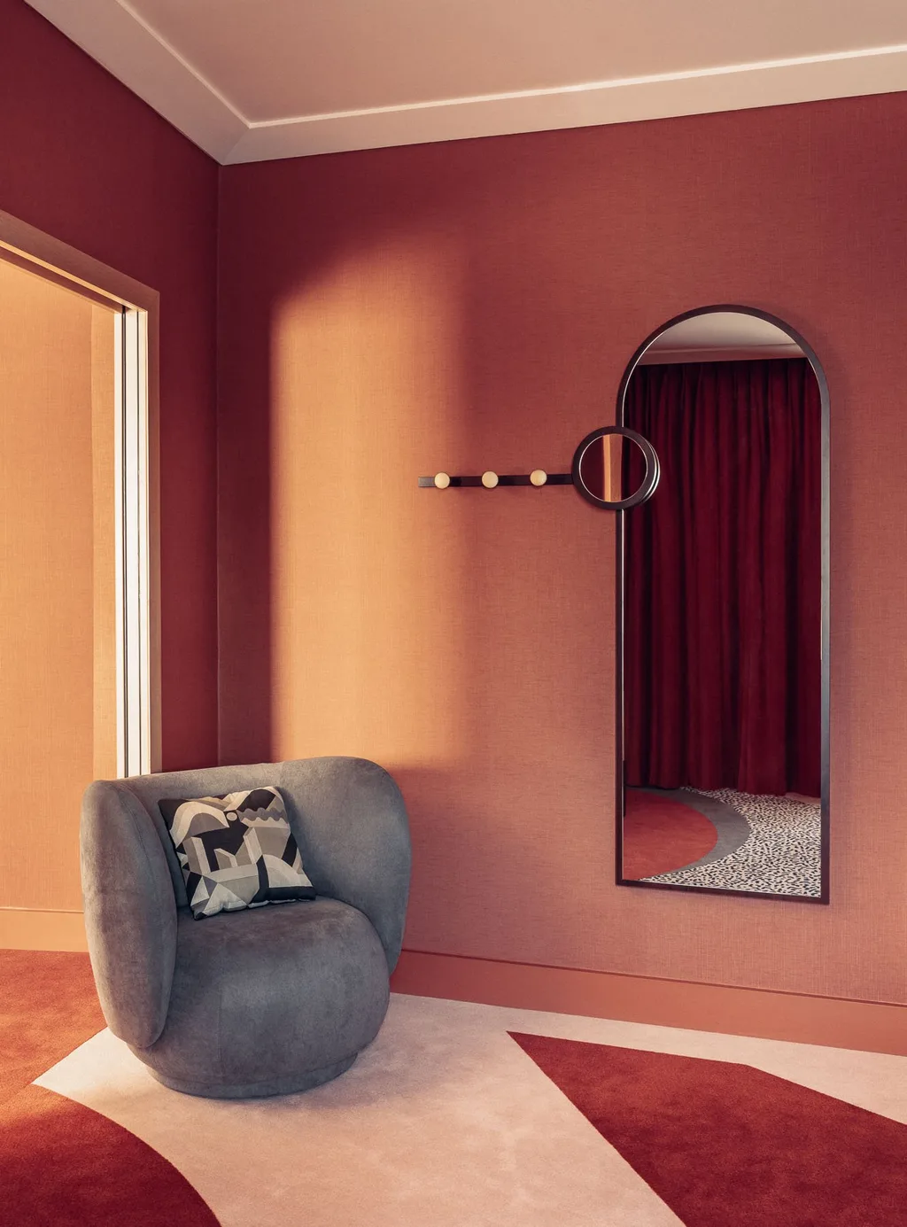 Corner nook with grey curved armchair and tall arched wall mirror, Nest MGallery Hotel, Paris