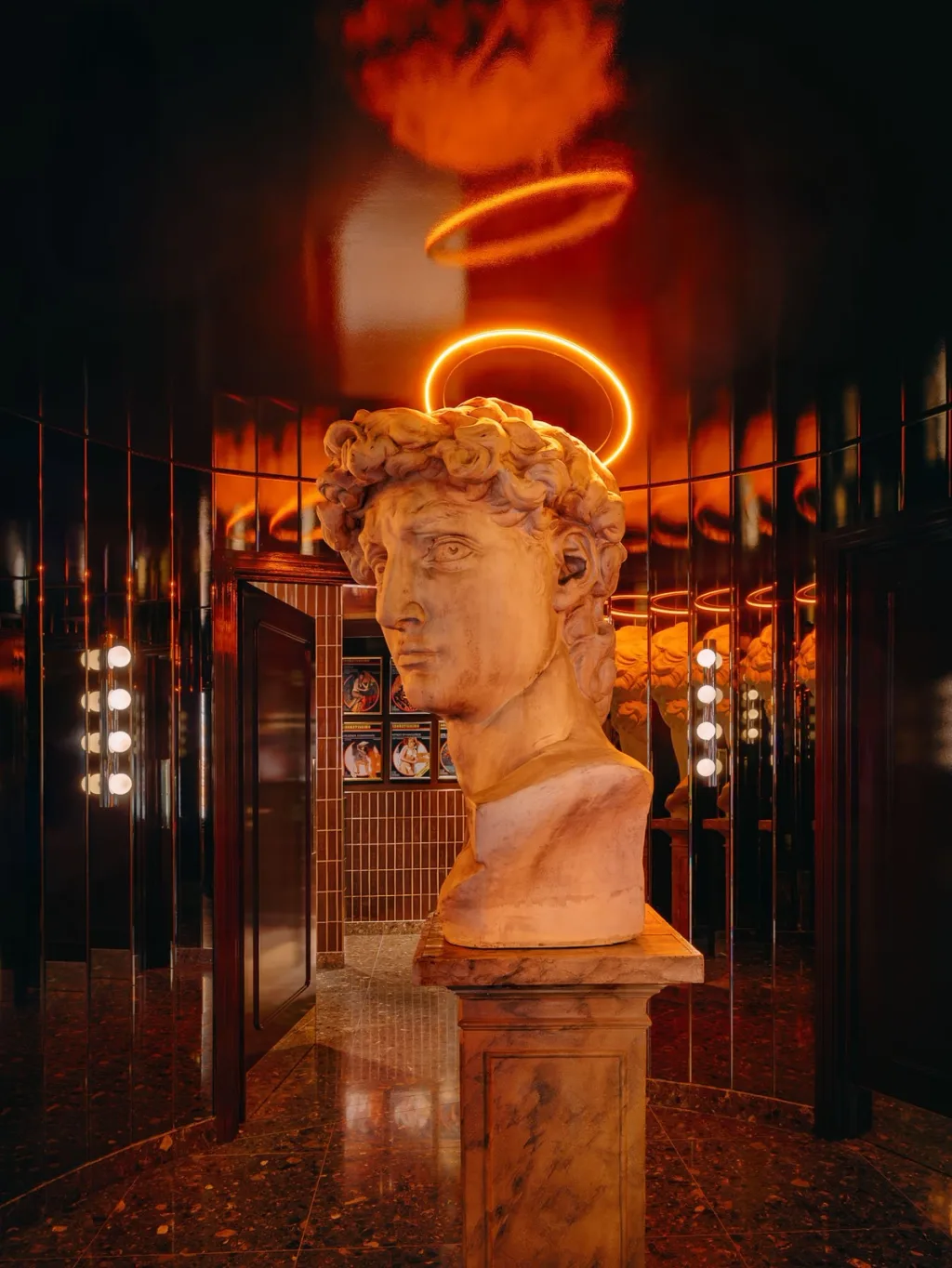 Classical bust beneath a glowing orange halo in a mirrored interior at Big Mamma, UK
