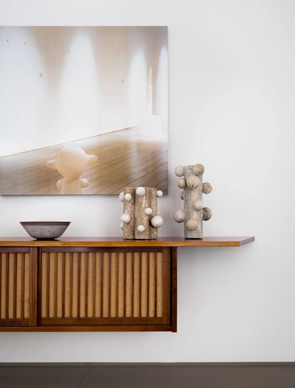 Two textured vessels on a slatted wooden cabinet beneath a photograph, Olivier Dwek, Paris