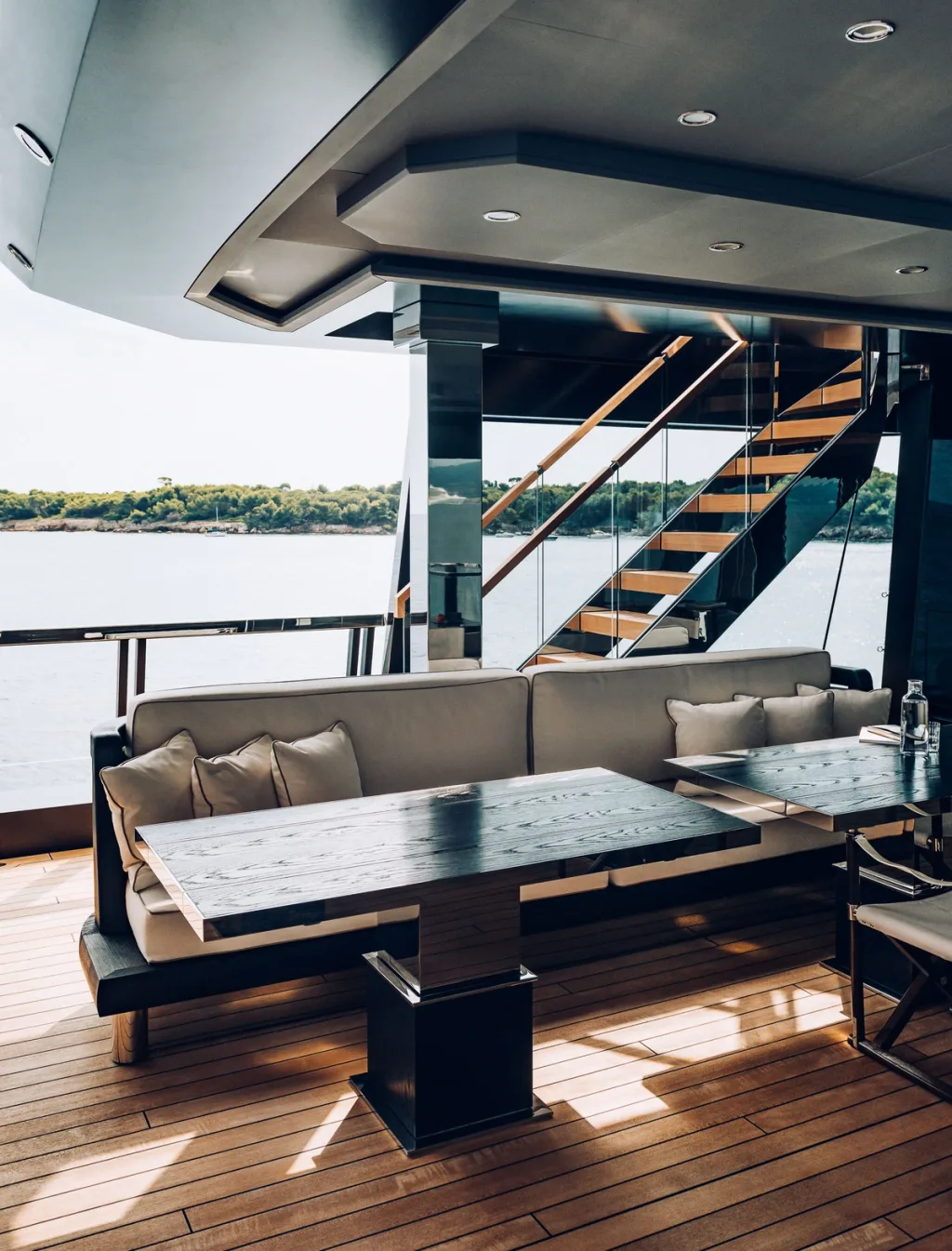 Sheltered dining bench beside an open staircase on the Atlante yacht deck