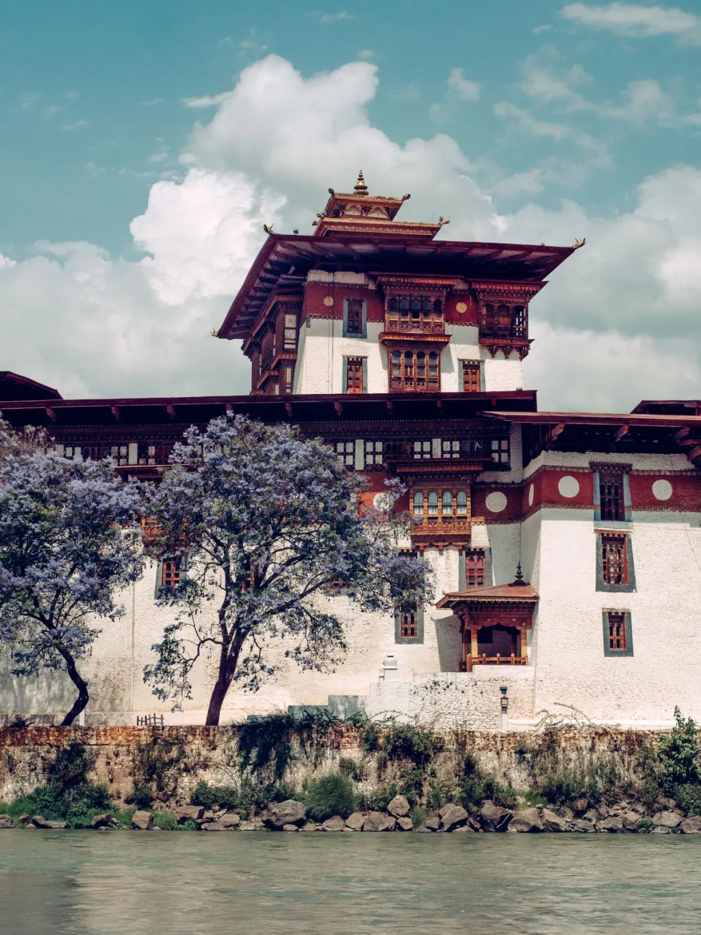 A riverside Bhutanese dzong with a flowering tree, photographed for Six Senses Bhutan hotel