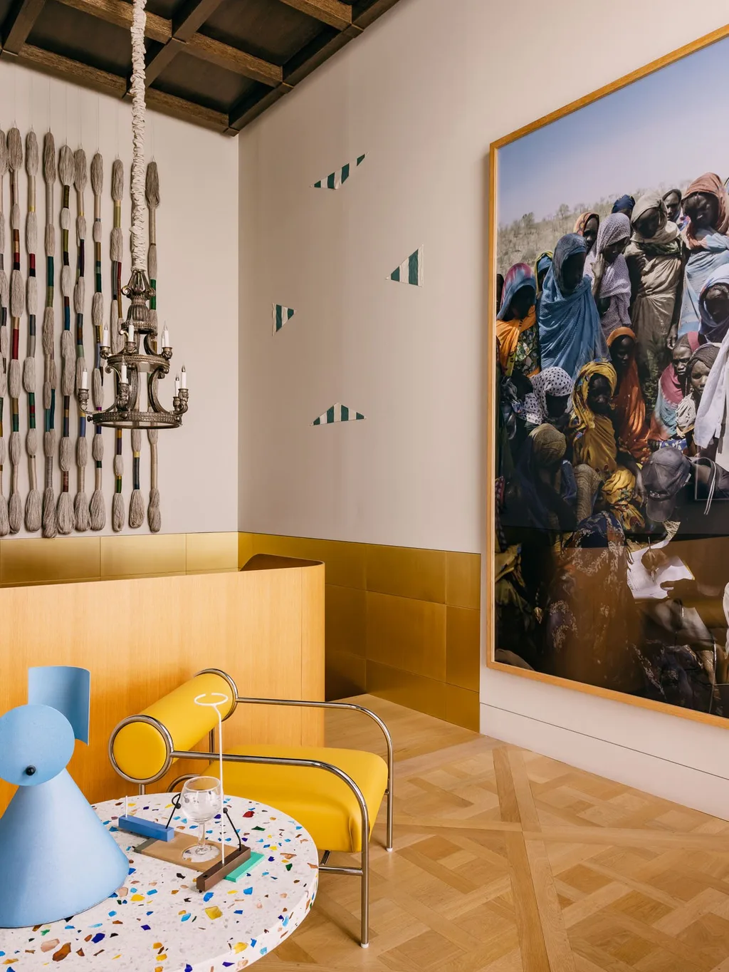 Yellow chair beside large artworks and a blue lamp in Laurent Buttazzoni's Paris interior