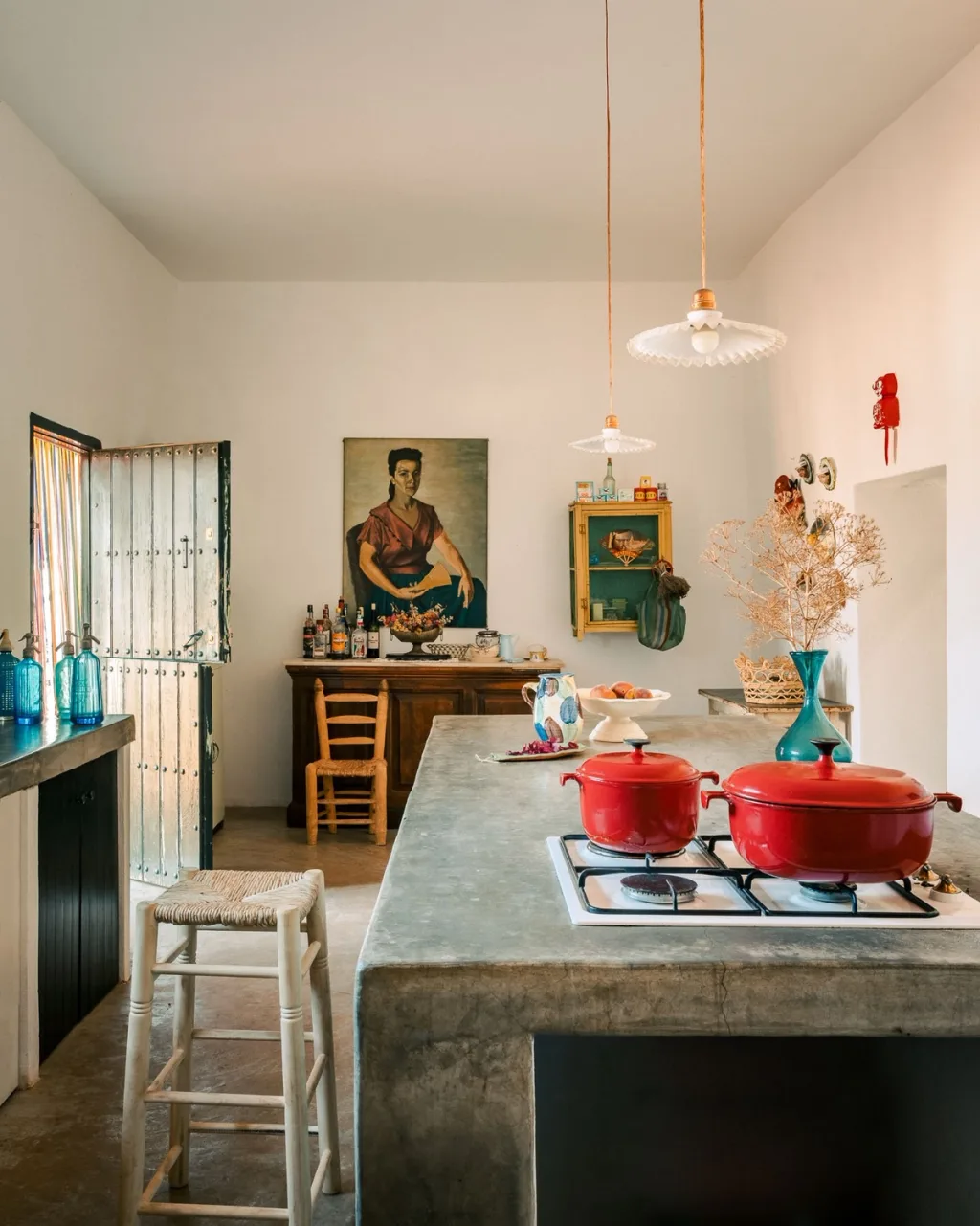 Red cooking pots on a long kitchen island with pendant lights in an Almeria home