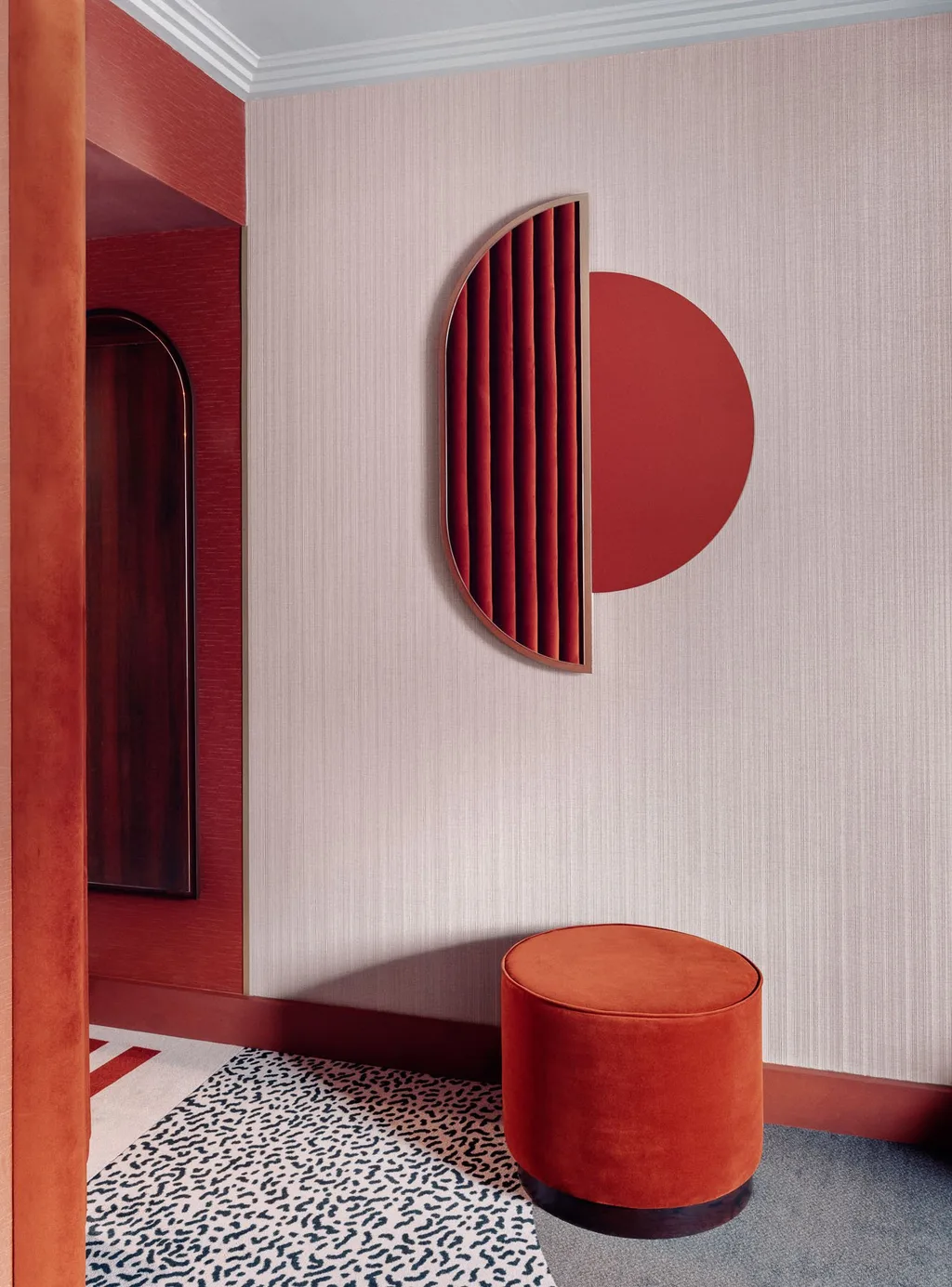 Blush wall with fluted red velvet sconce and round orange ottoman, Nest MGallery Hotel, Paris