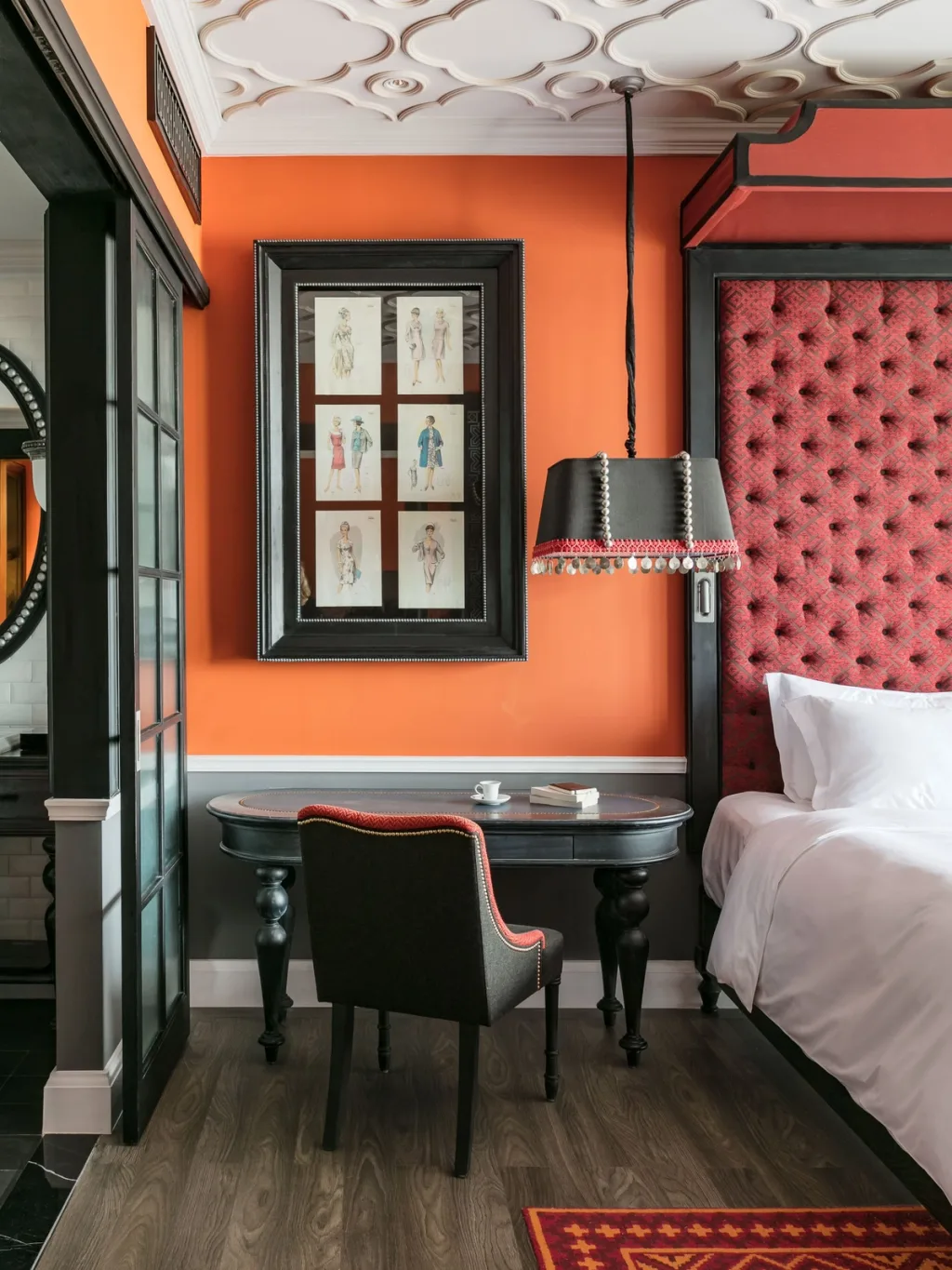 Orange bedroom with vintage fashion sketches and a red tufted headboard, Hotel de la Coupole MGallery, Sapa, Vietnam
