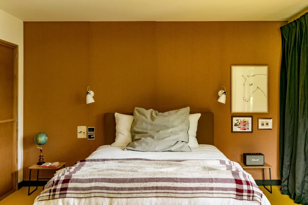 Ochre bedroom with a framed horse sketch and a plaid wool blanket, Le Barn hotel