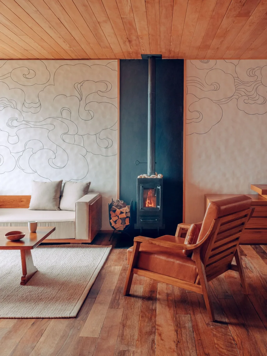 Lounge with cloud-motif walls and a lit wood-burning stove at Six Senses Bhutan hotel