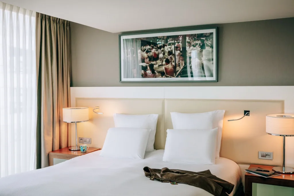 Framed street photograph above a bed with white pillows, Pullman Bercy hotel