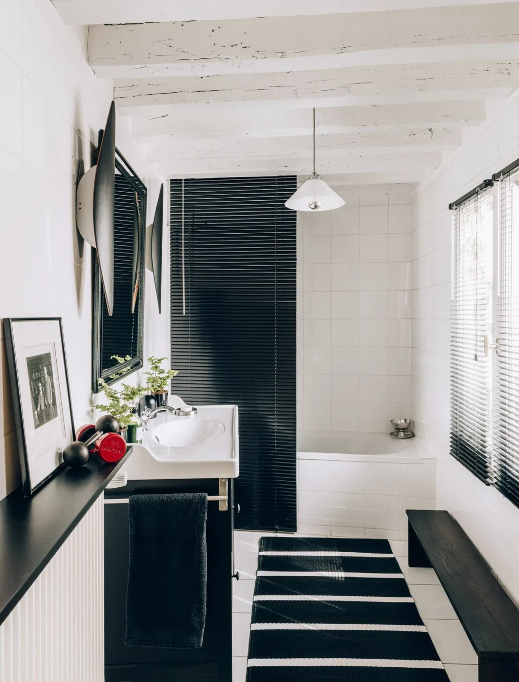 Black-and-white bathroom with striped rug, dark blinds and exposed beams, Michel Klein, Paris