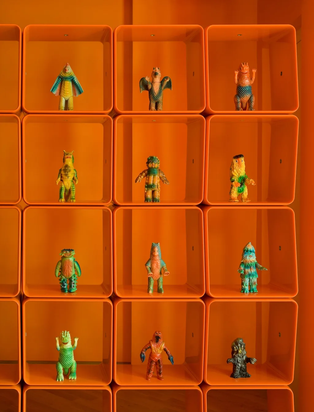 Colourful monster figurines displayed in orange wall cubbies in the Maurizio Galante series, Latina