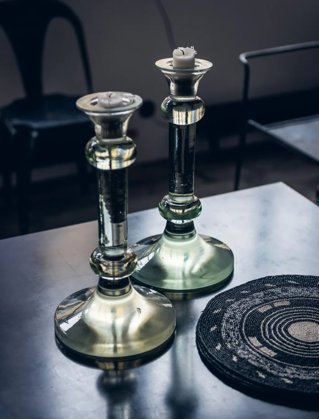 Two glass candlesticks on a reflective dining table at Daniel Rozensztroch's Paris home