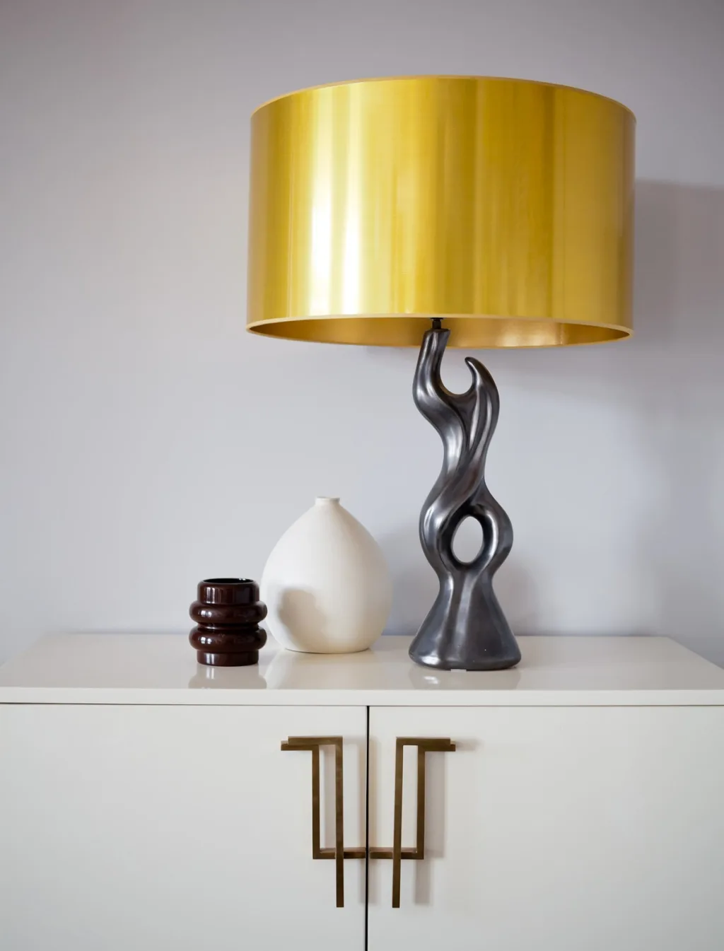Yellow-shaded sculptural lamp and two vessels on a white cabinet, Jean Louis Deniot, Paris