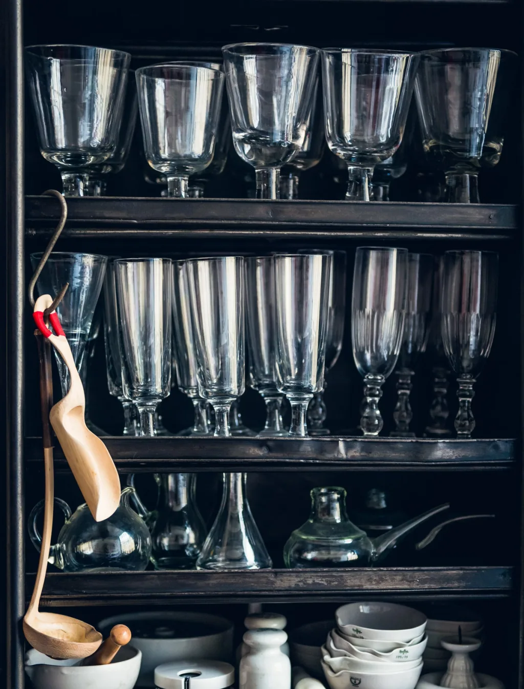 Rows of clear glasses and hanging wooden spoons at Daniel Rozensztroch's Paris home