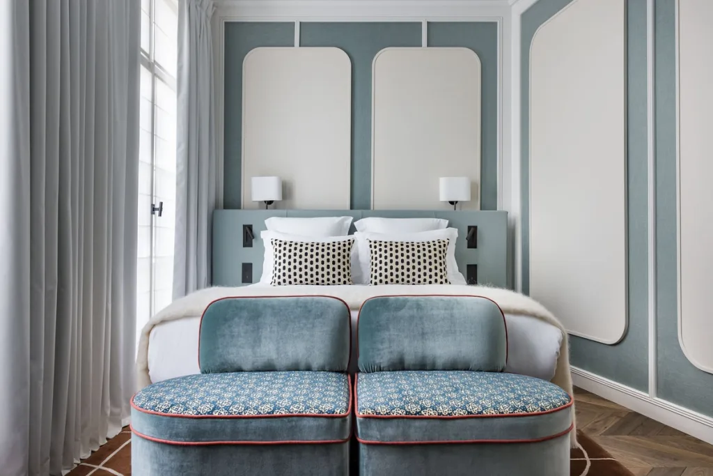Bedroom with a blue upholstered headboard and polka-dot cushions at Hotel Pavillon St Germain, Paris