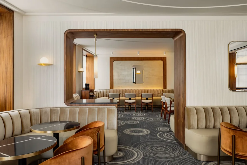 Dining room seen through a wood-framed archway with a gilded mirror at Hotel Pavillon St Germain, Paris