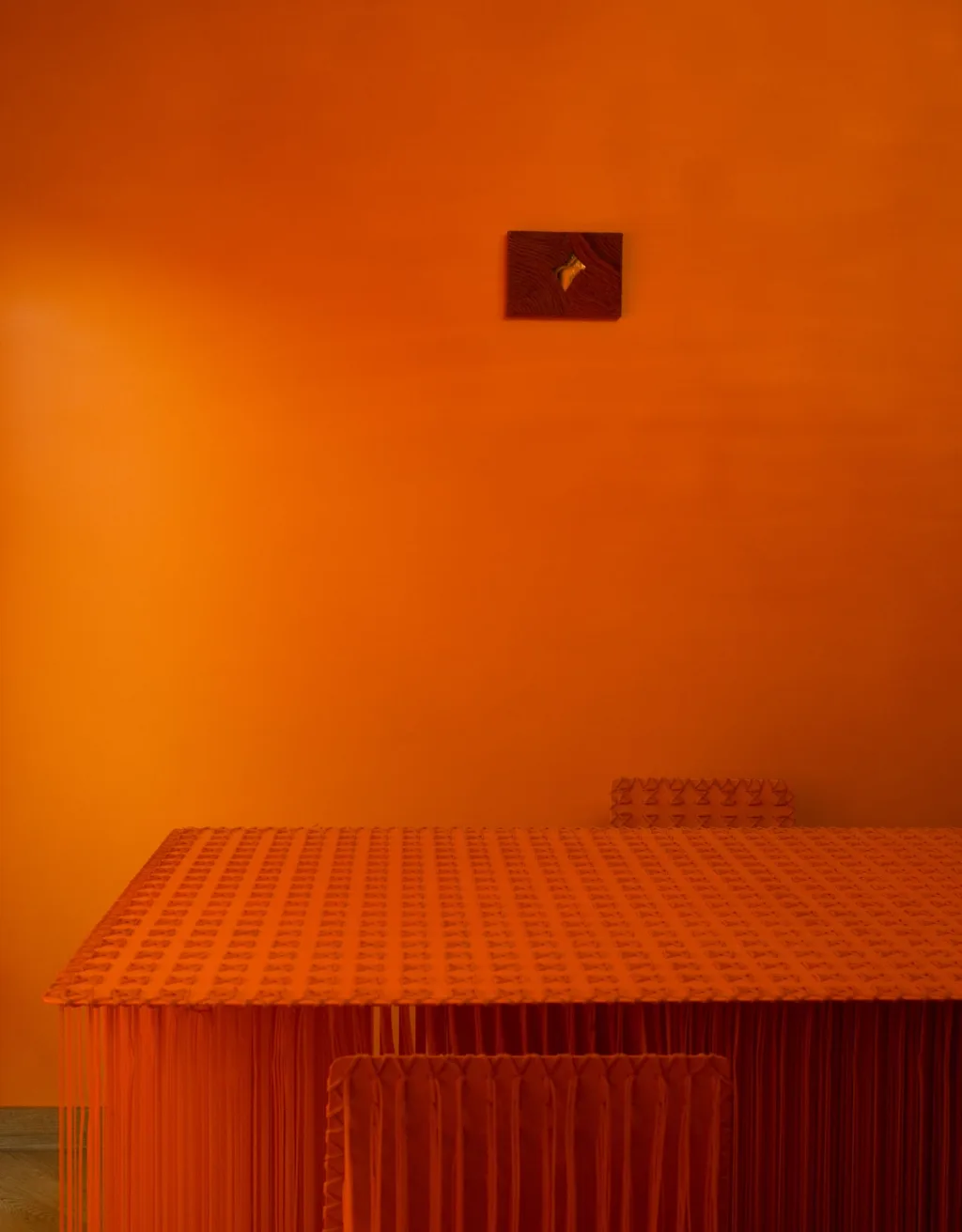 Textured orange table and chairs against a matching wall in the Maurizio Galante interior, Latina