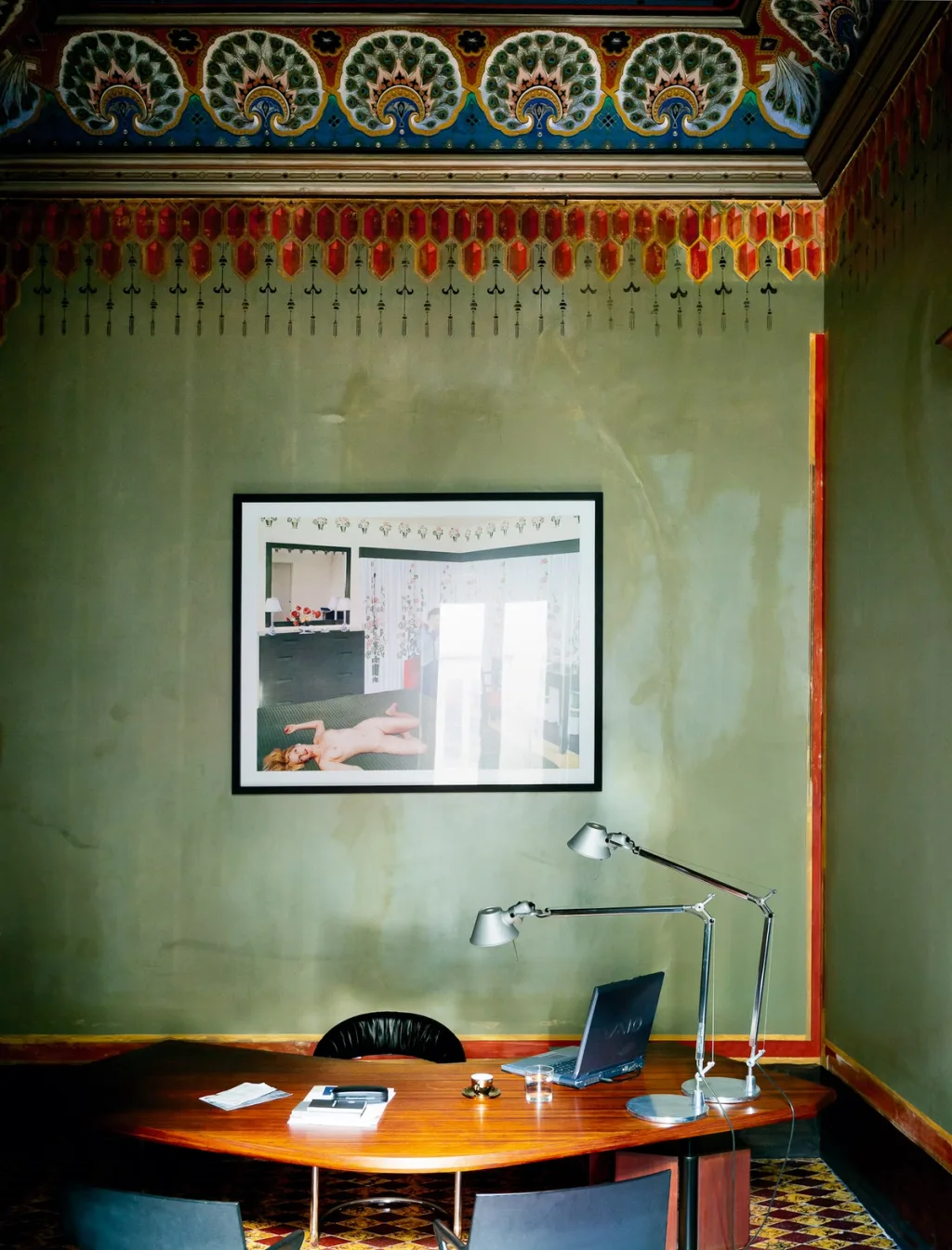 Oval desk beneath a decorative wall border in the Antonio G. Martiniello interior, Naples