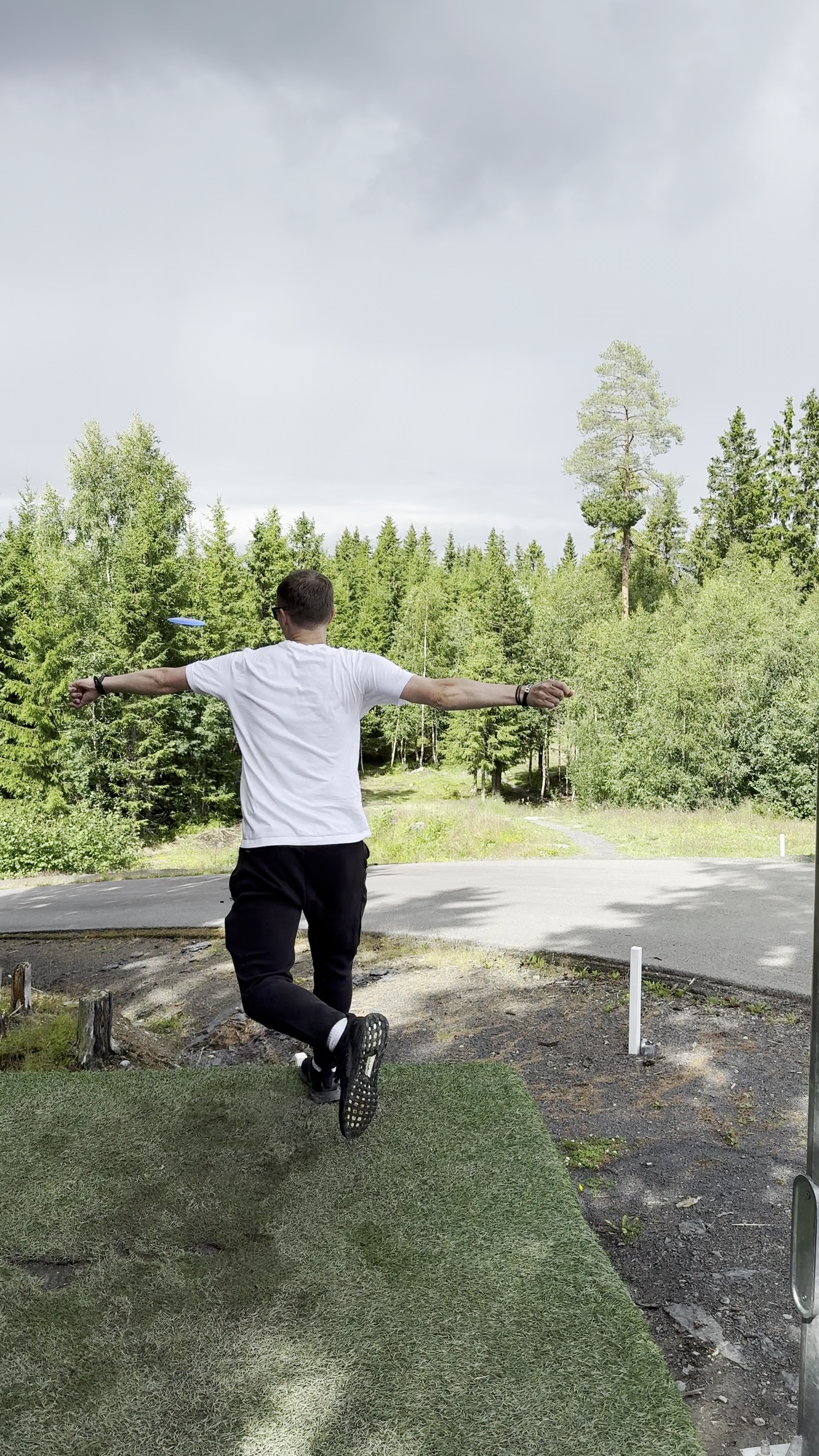Man throwing disc into forest