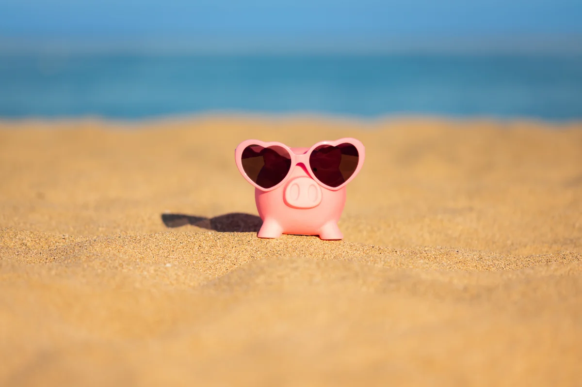 Tirelire en forme de cochon avec des lunettes sur une plage de sable