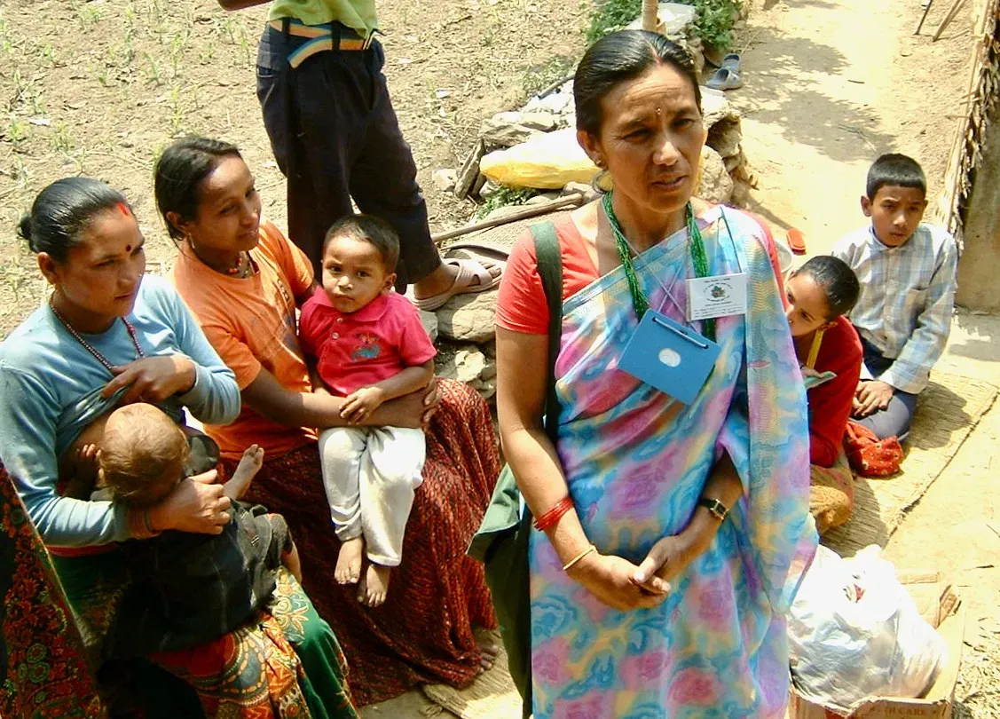 A female community health volunteer (FCHV) at a meeting of local mothers explains her work in the area