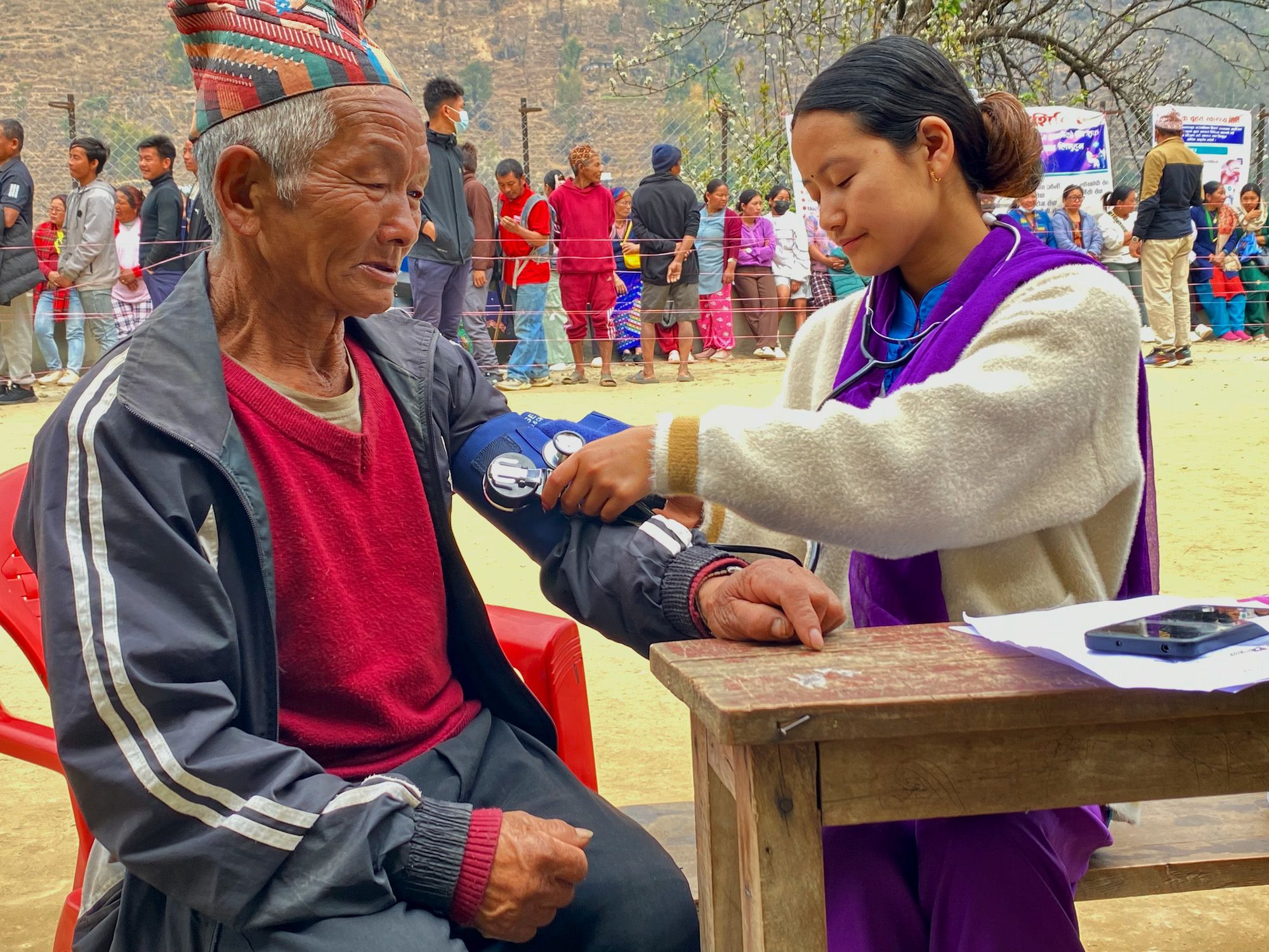 A nurse takes the blood pressure of an elderly man, one of the community residents receiving medical help from a mobile health camp set up in Taplejung District in northeast Nepal.