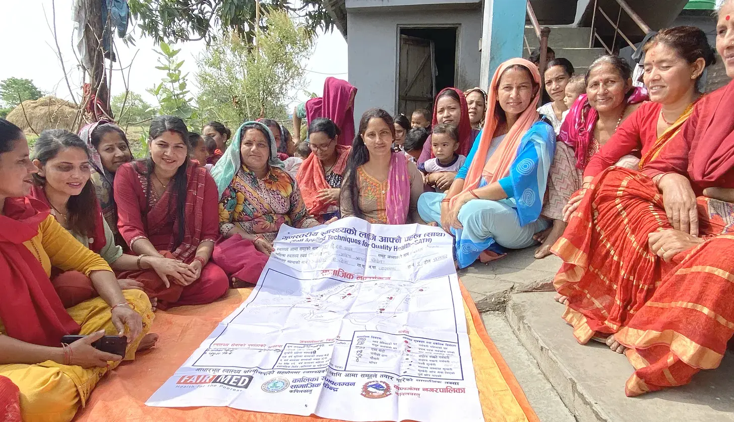 Members of a women's group in Kapilvastu District, Nepal, sit around a poster-like tool that they use to track the 'progress' of pregnant women and new mothers in the group.
