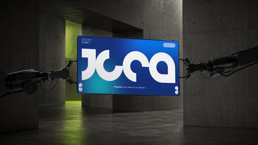 Robotic arms holding a screen displaying JCCA logo in a dim industrial space with concrete walls.