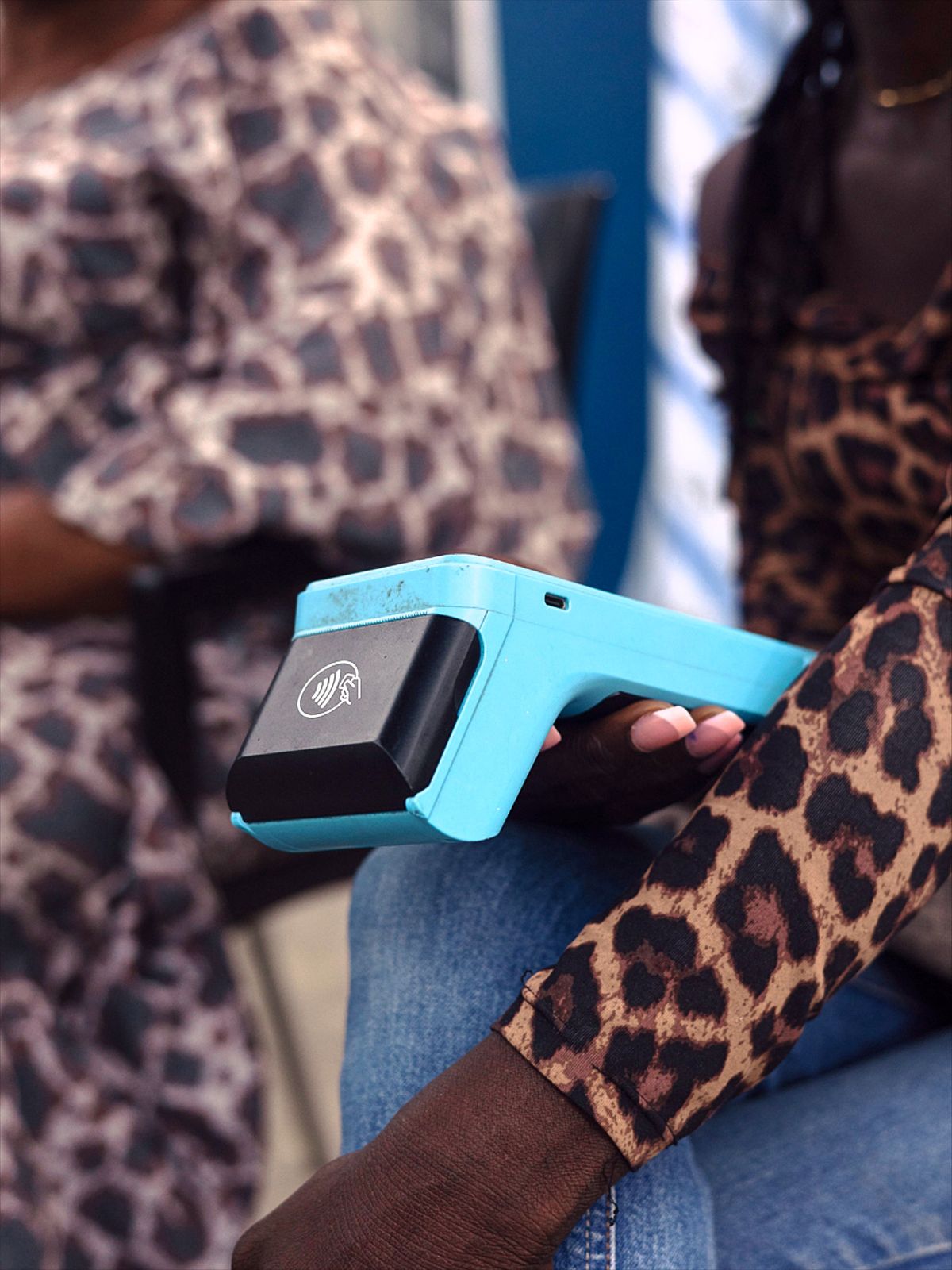 close up of point of sale machine held by a young Nigerian women wearing leopard print