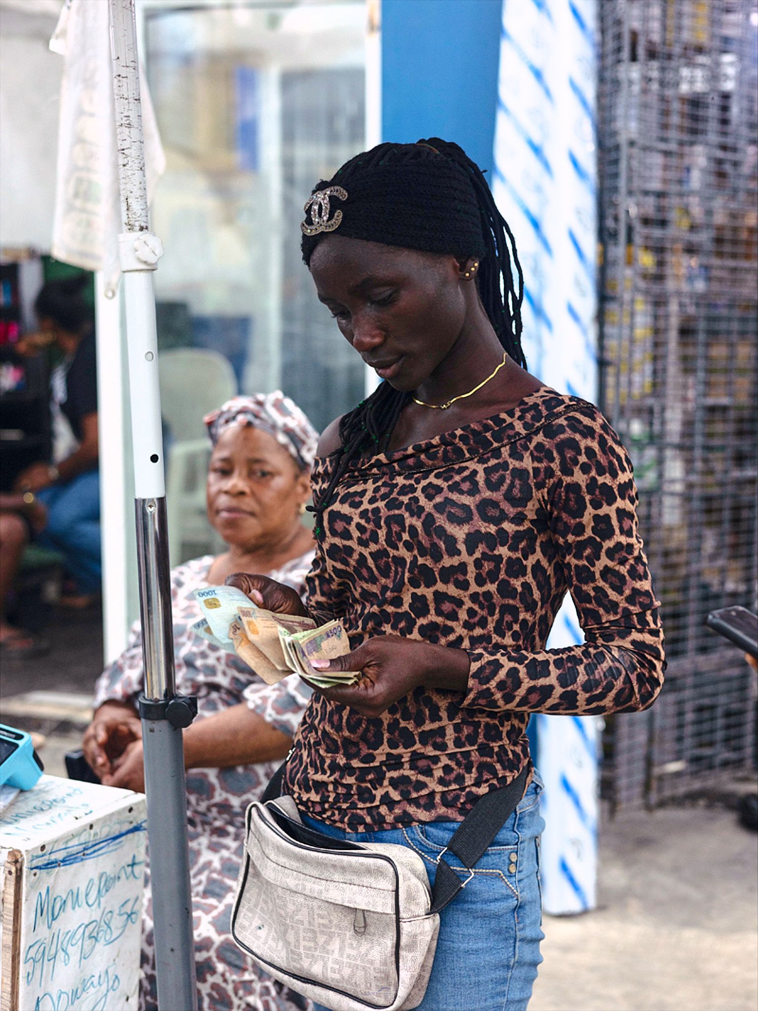 Young women counting money wearing leopard print in the lagos streets
