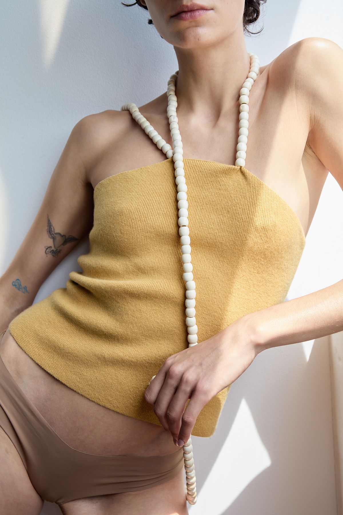 woman in yellow vest with beaded necklace