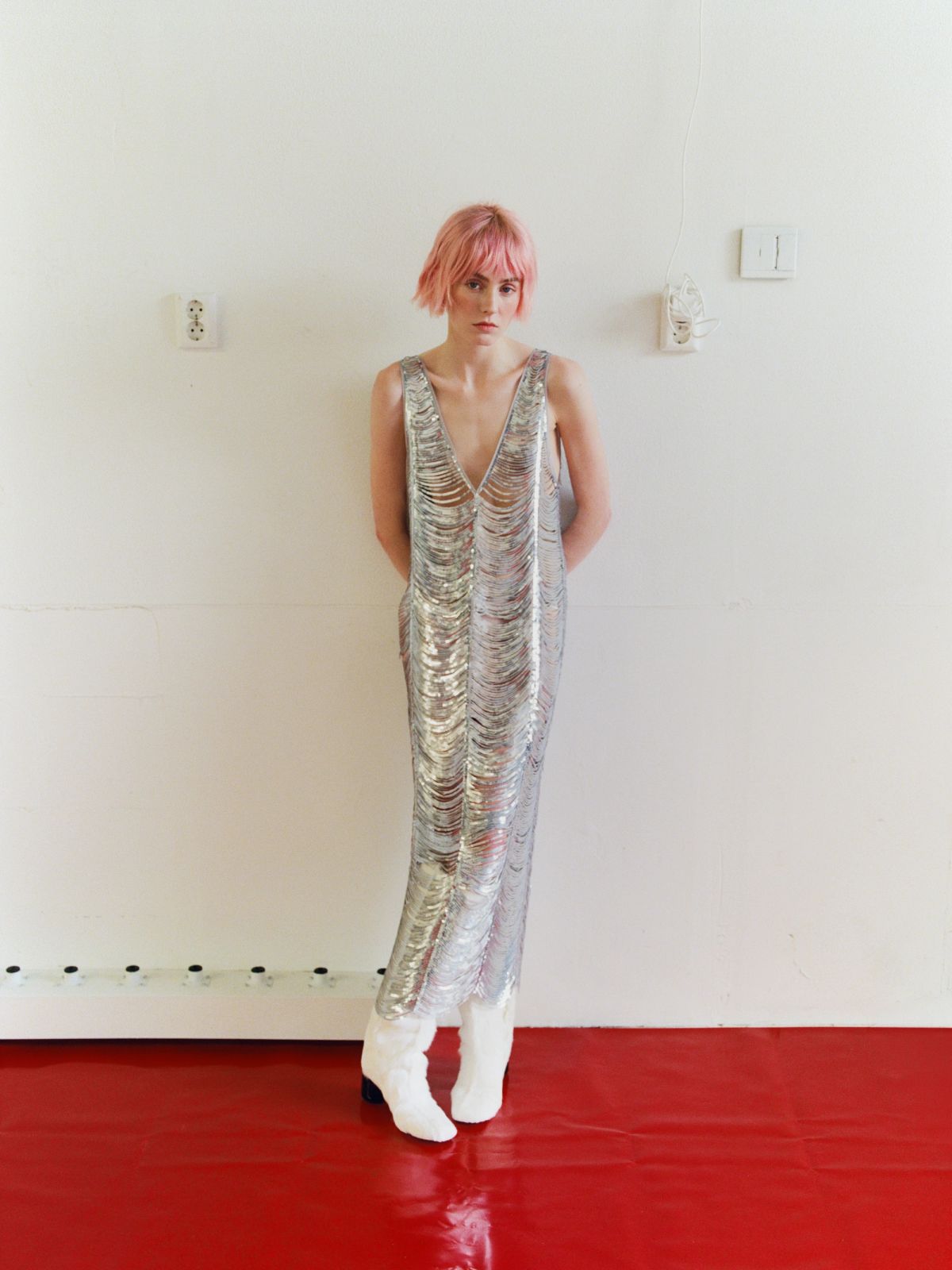 women in silver dress leaning against a wall
