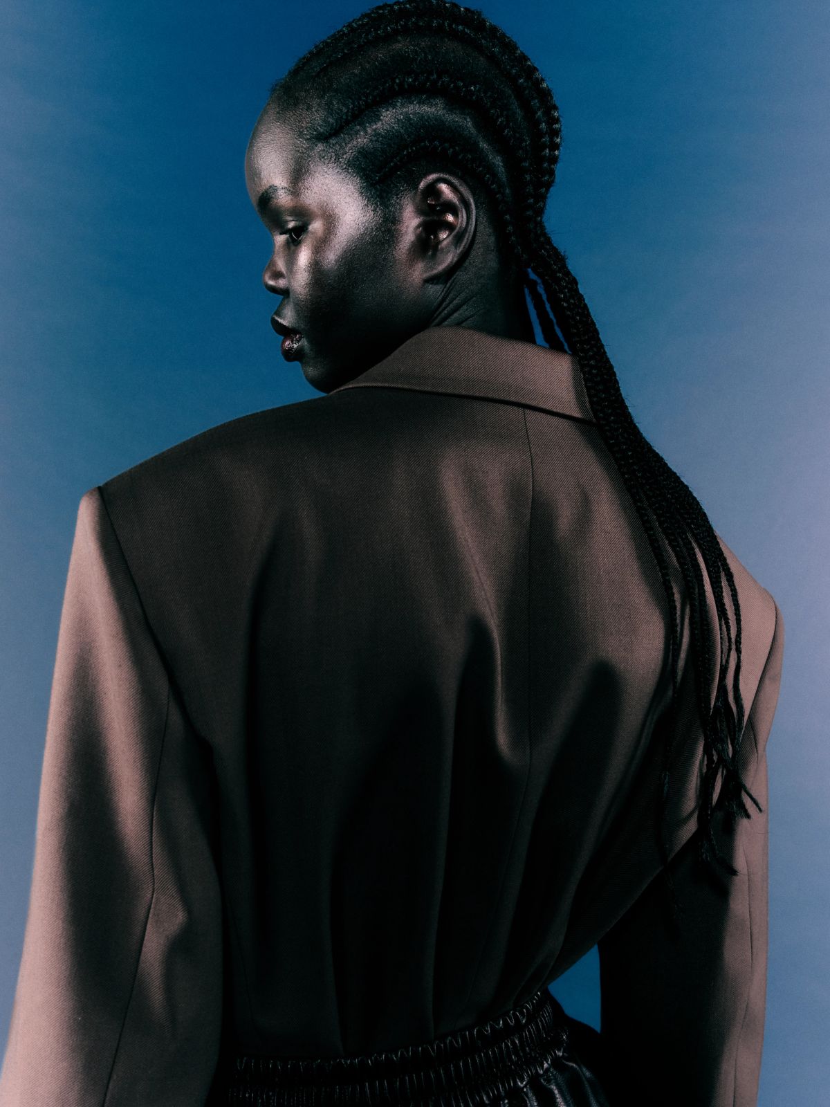 model on blue background with back to camera and braids in her hair