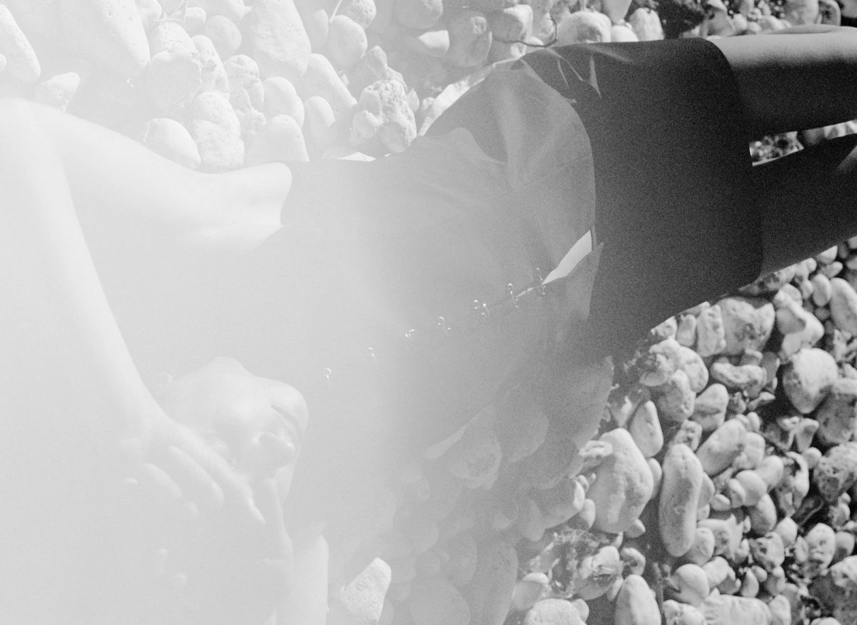 Woman lying on pebbles with hands on head