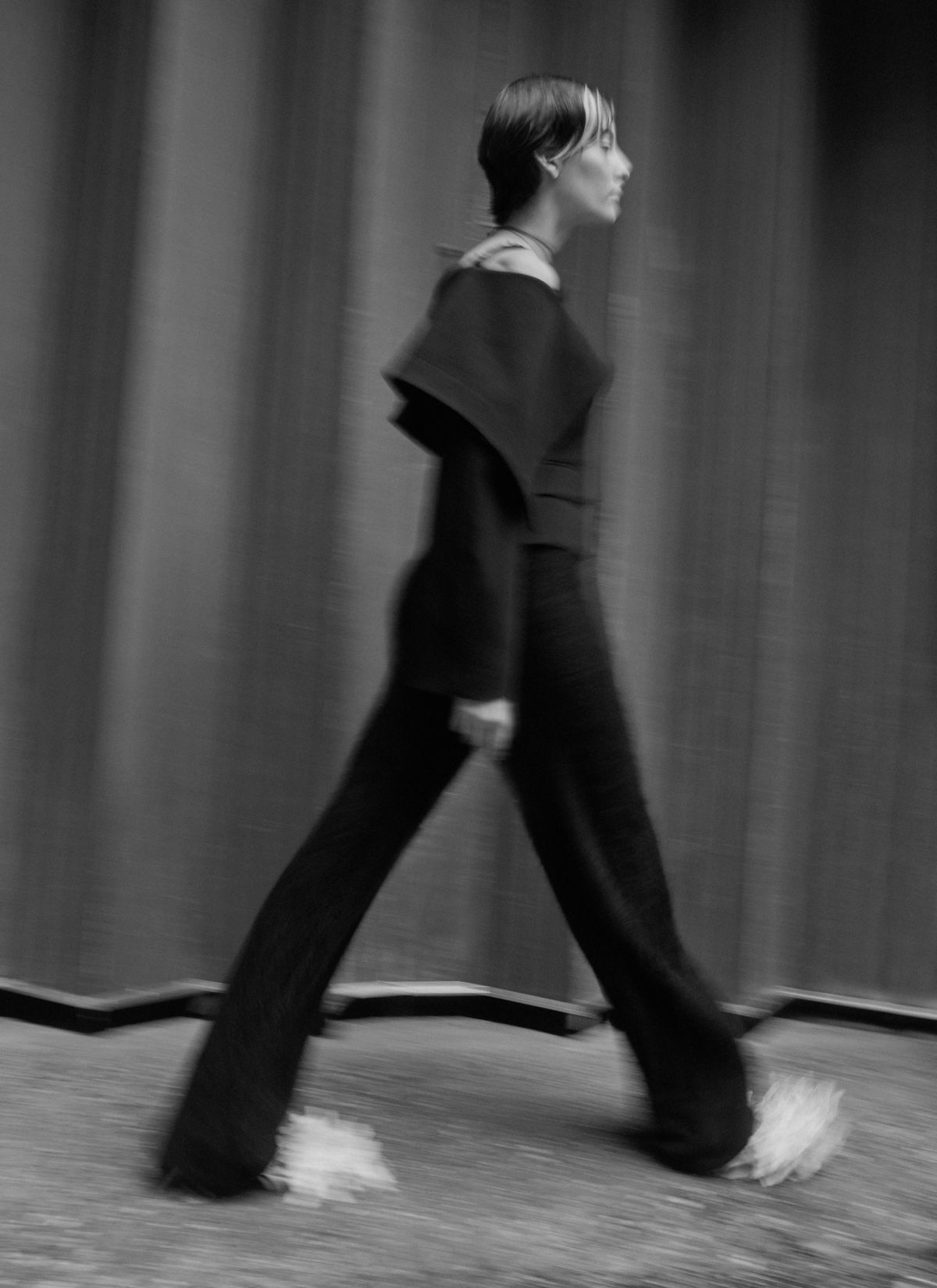 model wearing black with white shoes walking outside with a soft blur