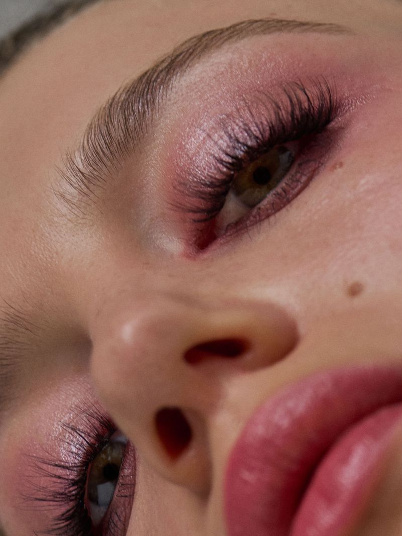 extreme close up of models face, long lashes, soft pink eyeshadow and muted pink lips