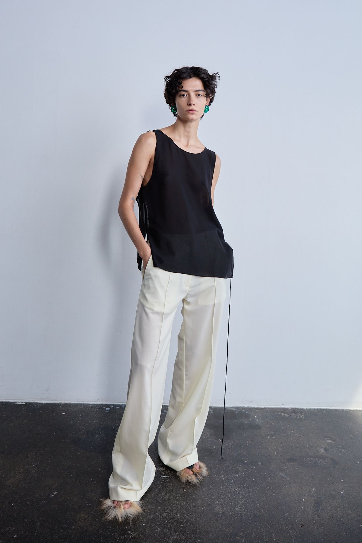 Woman standing in black top and cream trousers