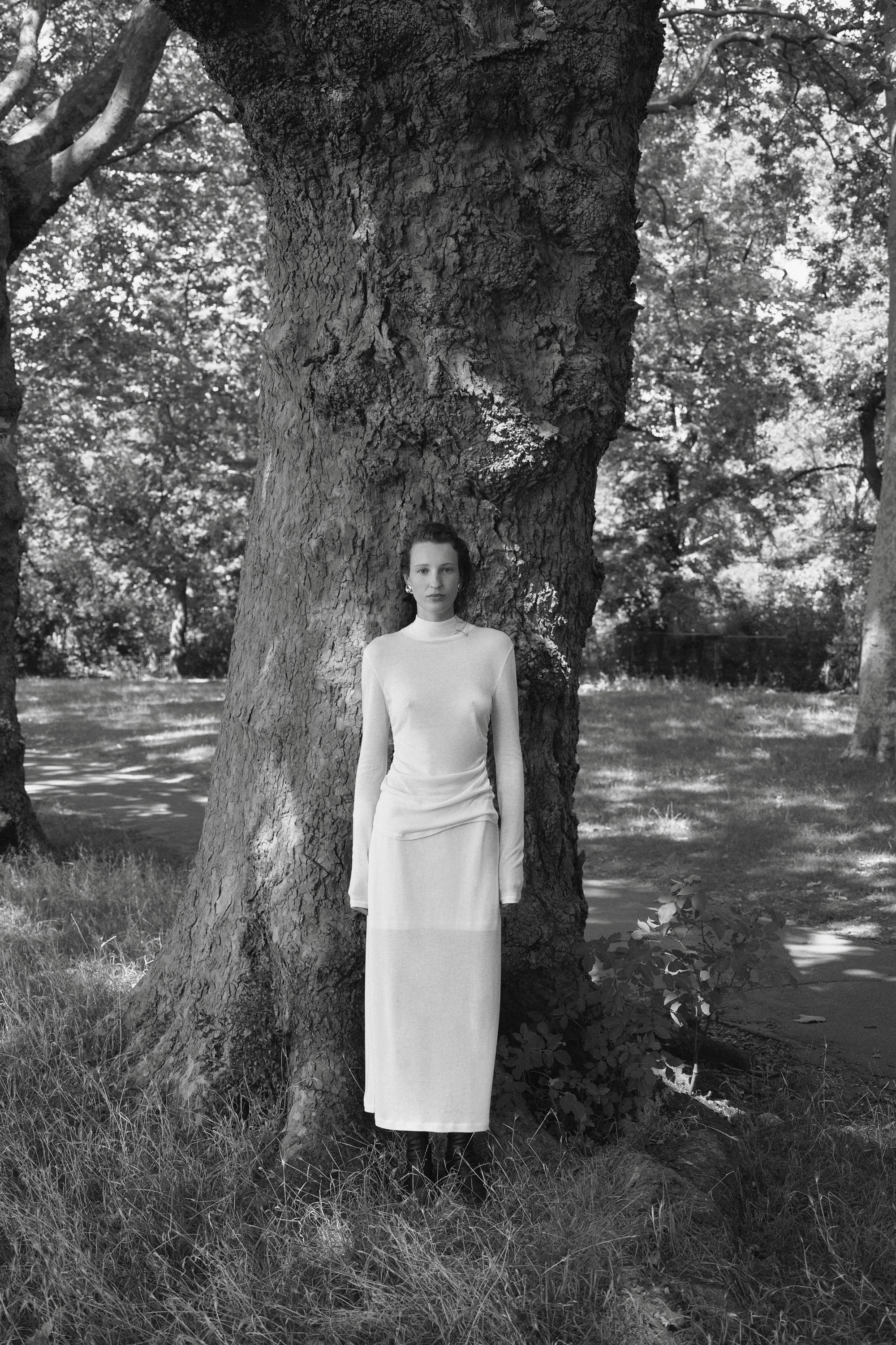Woman standing by tree wearing all white