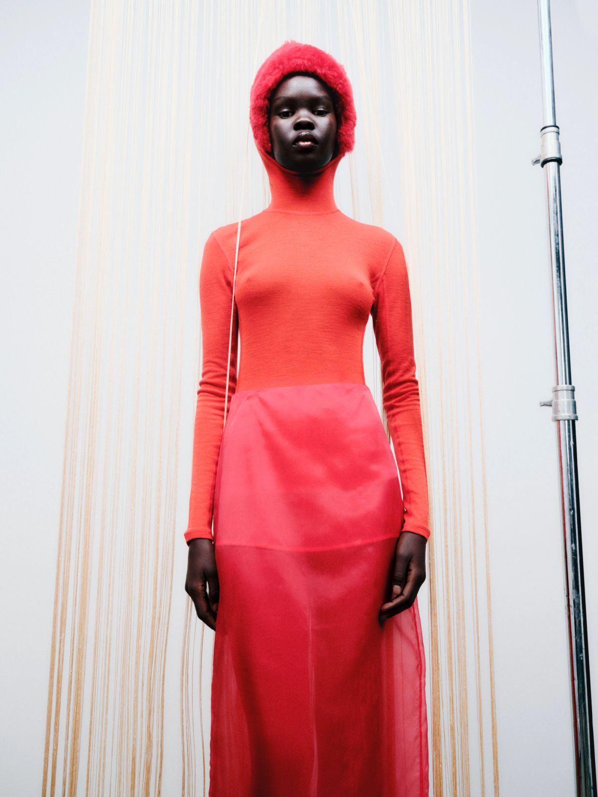 model wearing red and a red bonnet on a white background with fringing