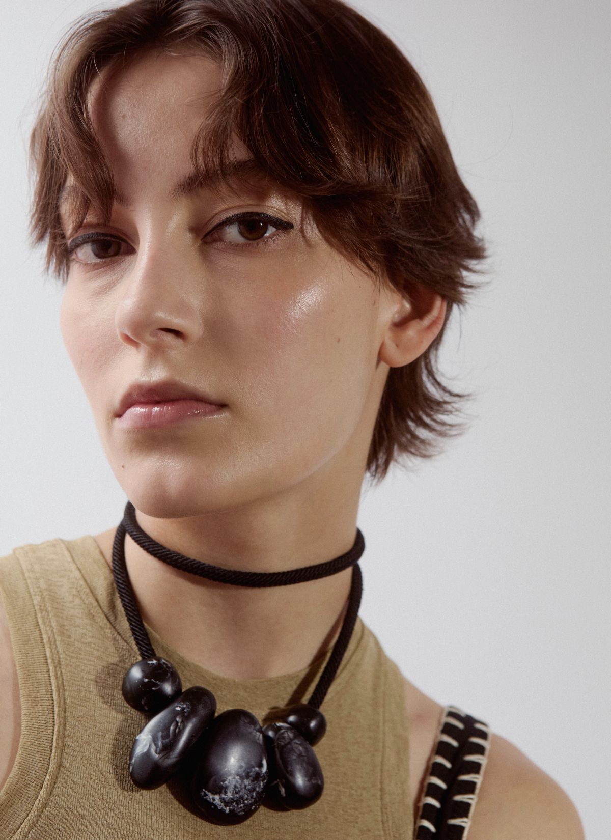 close up of model on white background looking to camera wearing necklace