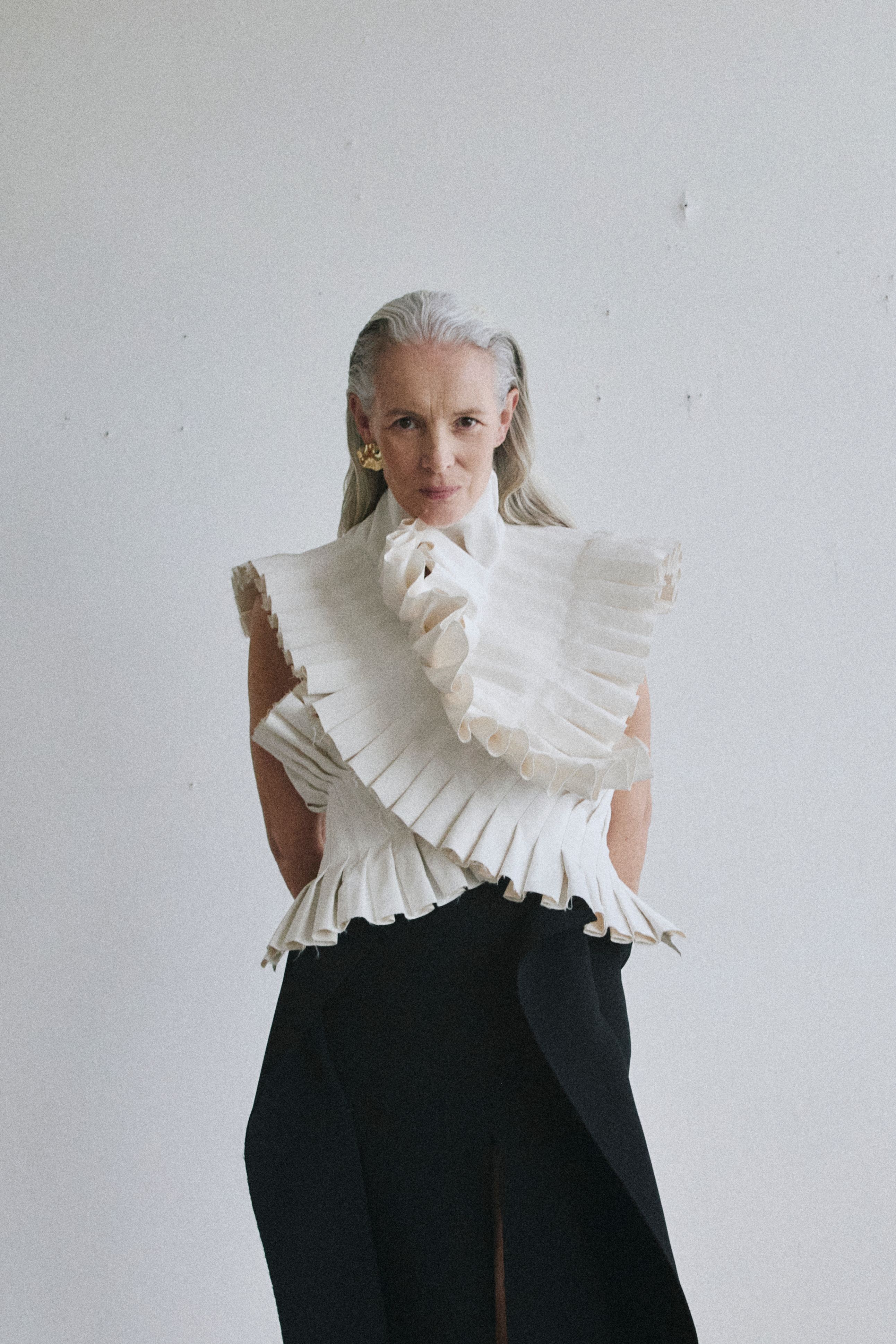 women stares to camera, wearing white ruffle top and black trousers