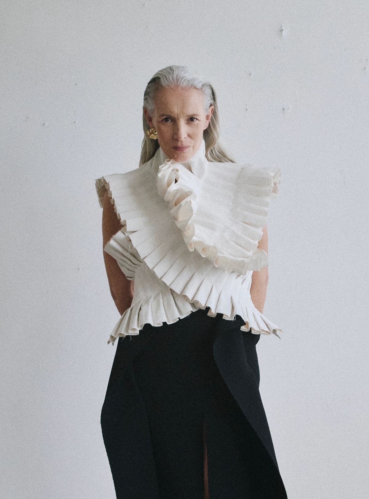women stares to camera, wearing white ruffle top and black trousers