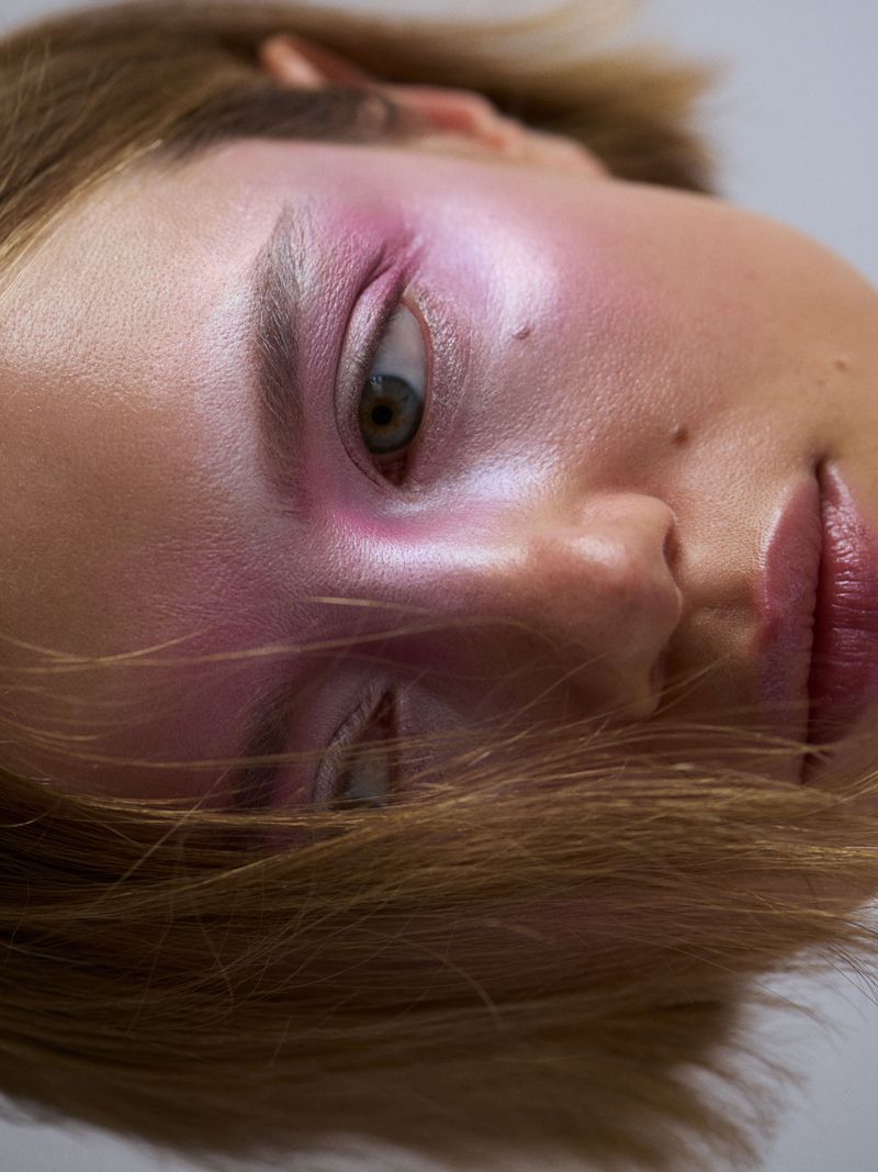 Close up of a model with pink make up across her eyes, eyebrows and nose
