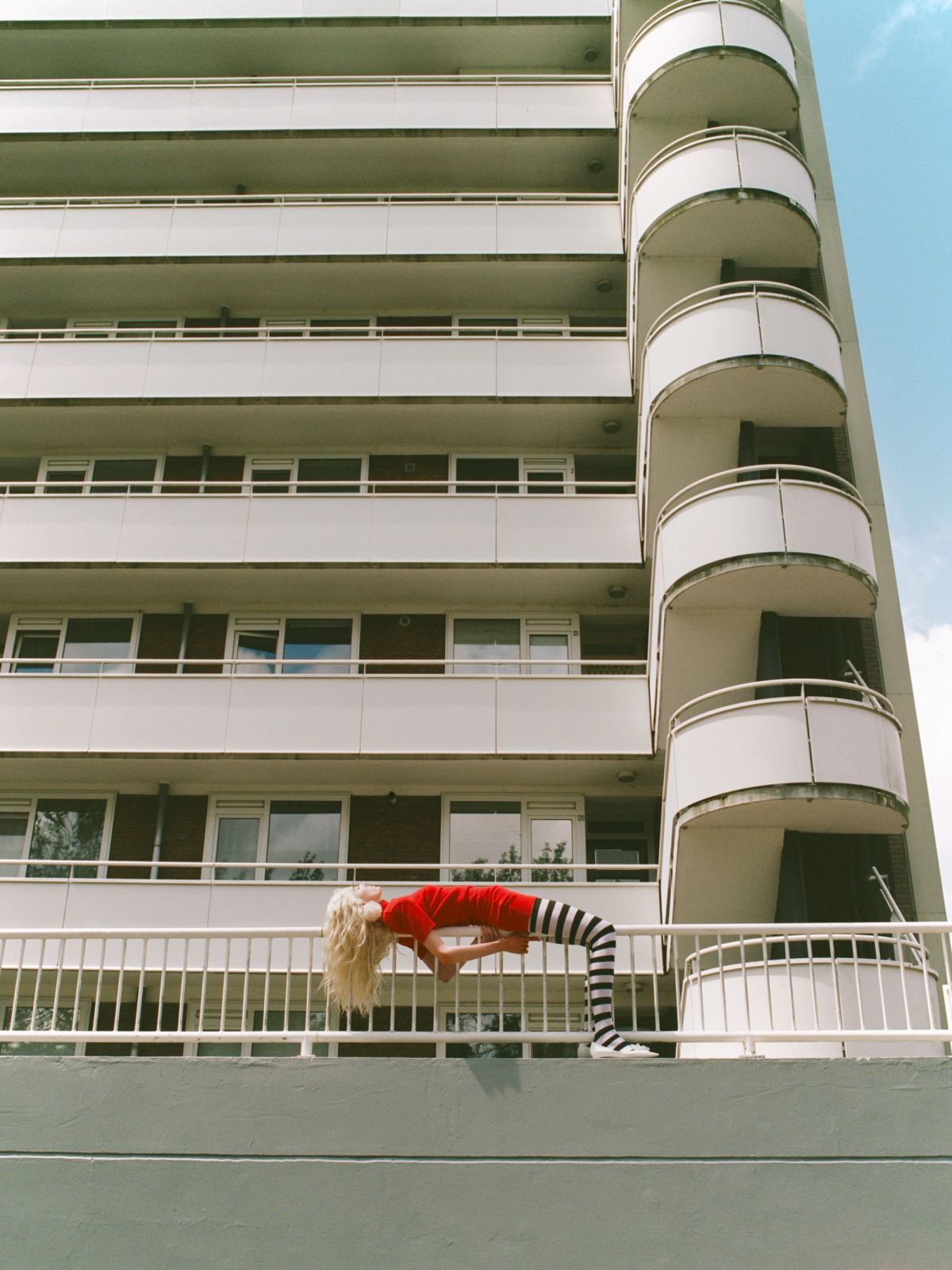 Women in red lying on railings in front of a white building