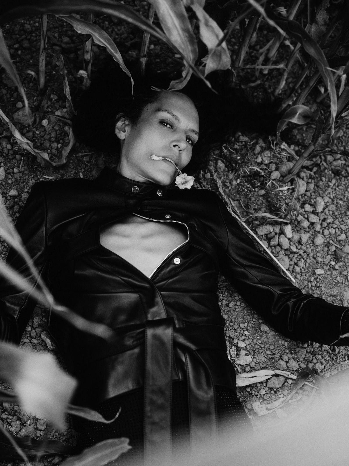 model lying down in a corn field wearing black
